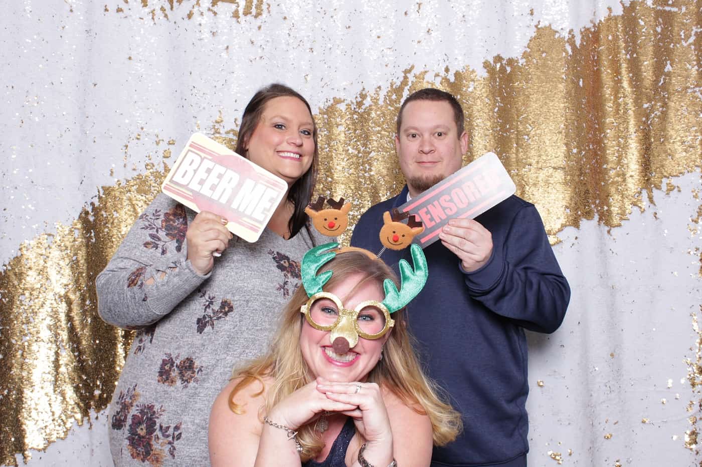 company christmas party photo booth photo taken against a white and gold sequin backdrop with christmas props