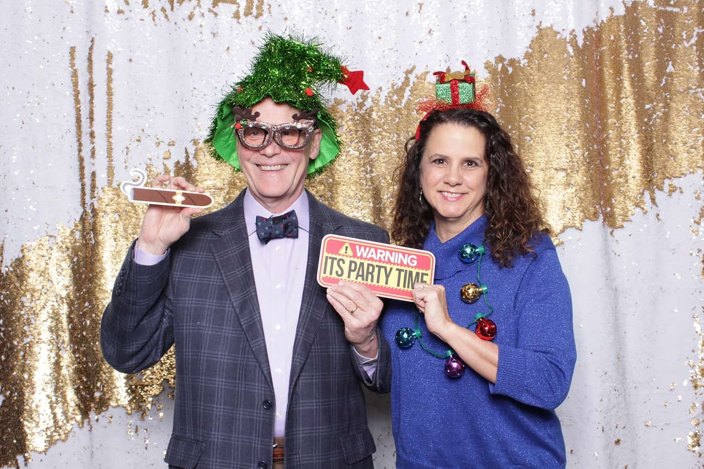 company christmas party photo booth photo taken against a white and gold sequin backdrop with christmas props