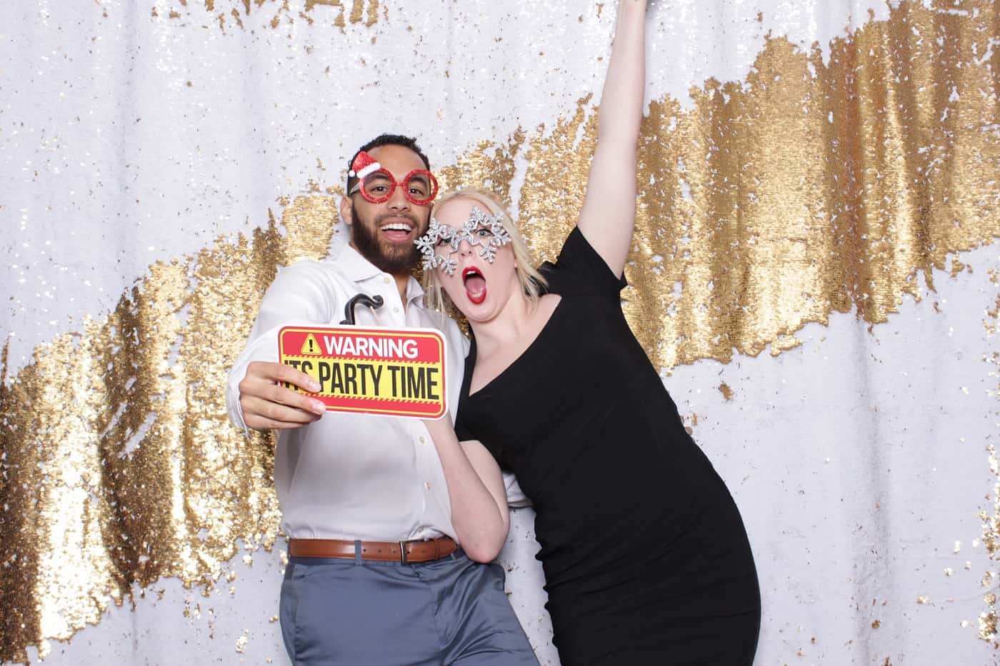 company christmas party photo booth photo taken against a white and gold sequin backdrop with christmas props