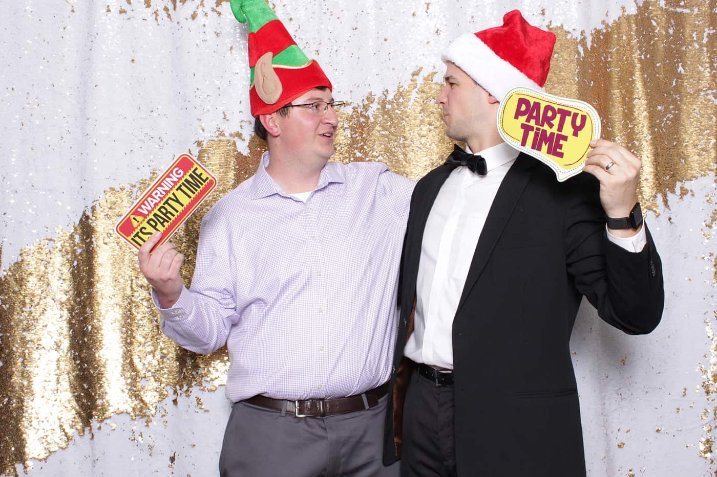 company christmas party photo booth photo taken against a white and gold sequin backdrop with christmas props