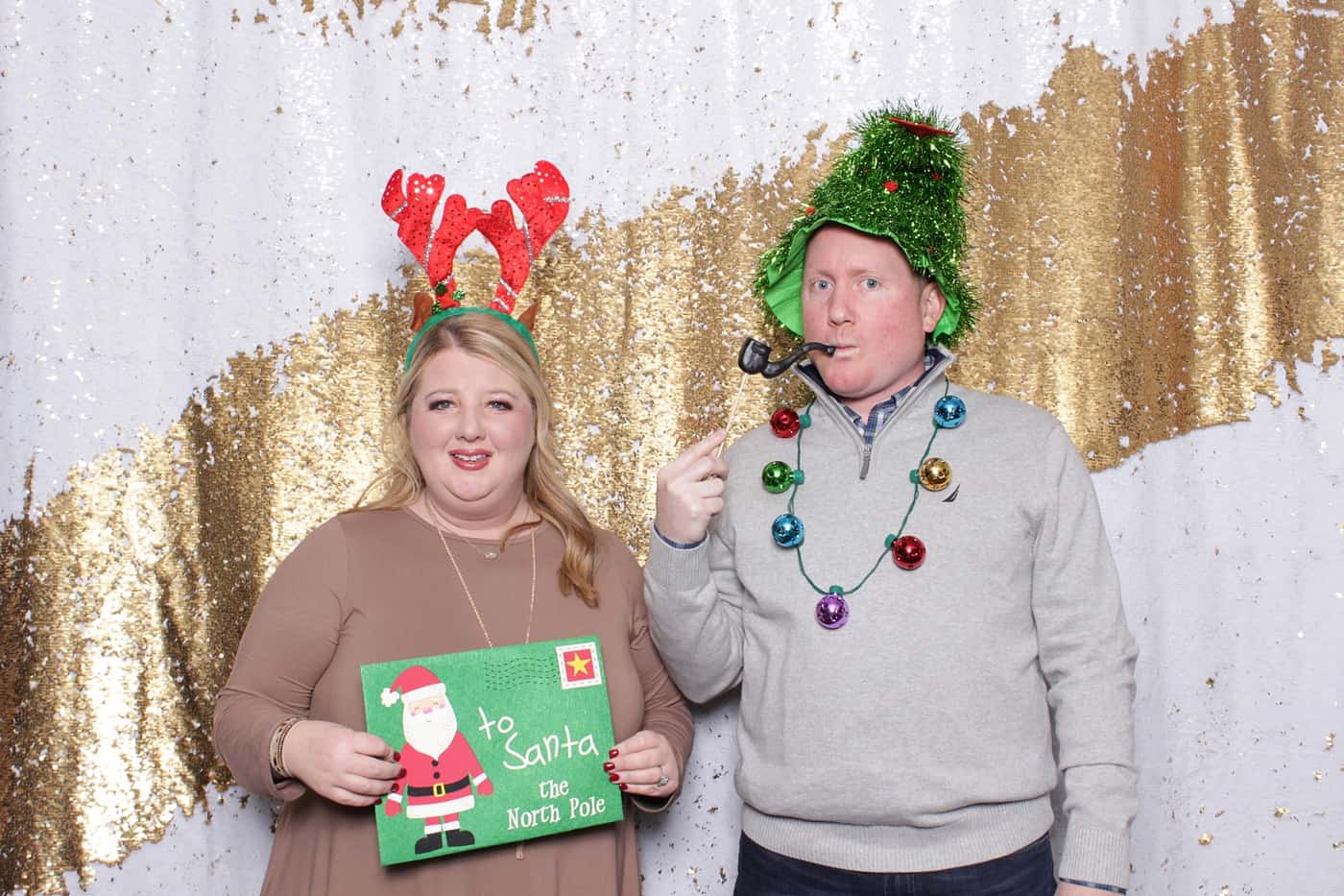 company christmas party photo booth photo taken against a white and gold sequin backdrop with christmas props