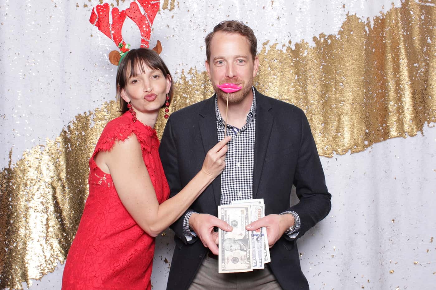 company christmas party photo booth photo taken against a white and gold sequin backdrop with christmas props