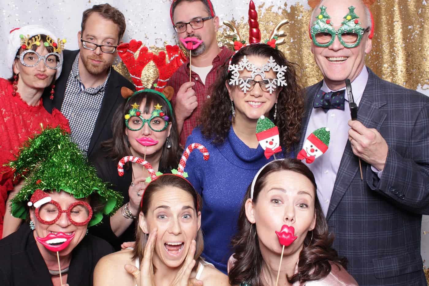 company christmas party photo booth photo taken against a white and gold sequin backdrop with christmas props