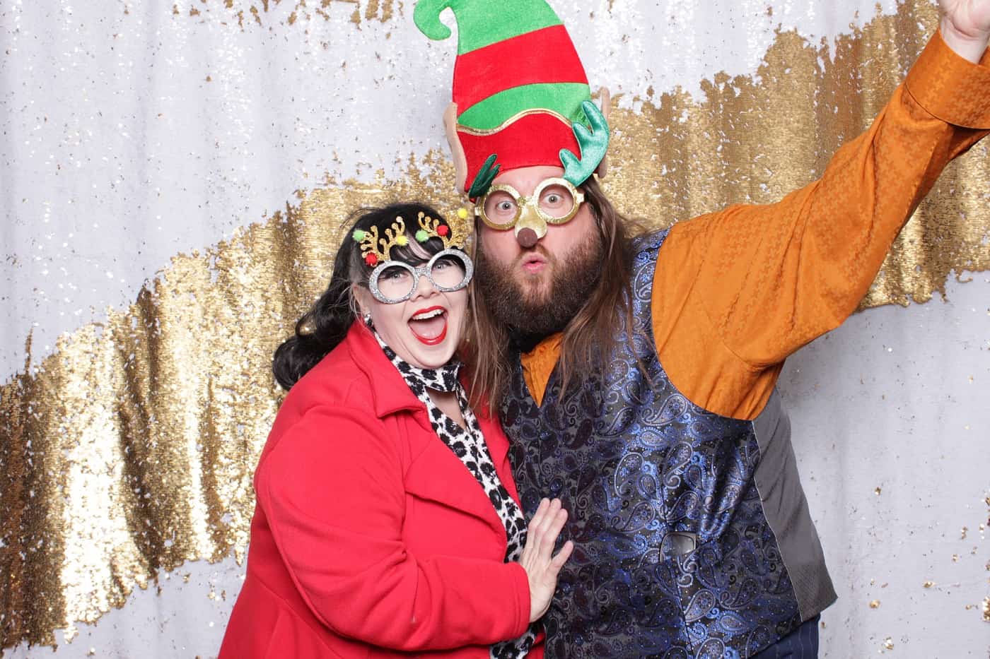 company christmas party photo booth photo taken against a white and gold sequin backdrop with christmas props