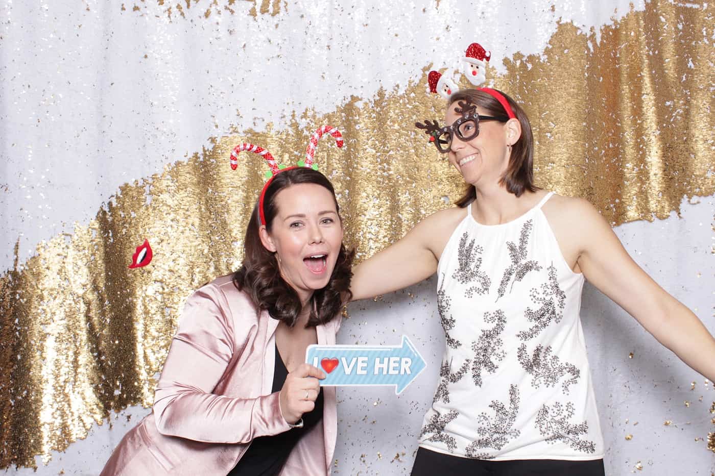 company christmas party photo booth photo taken against a white and gold sequin backdrop with christmas props