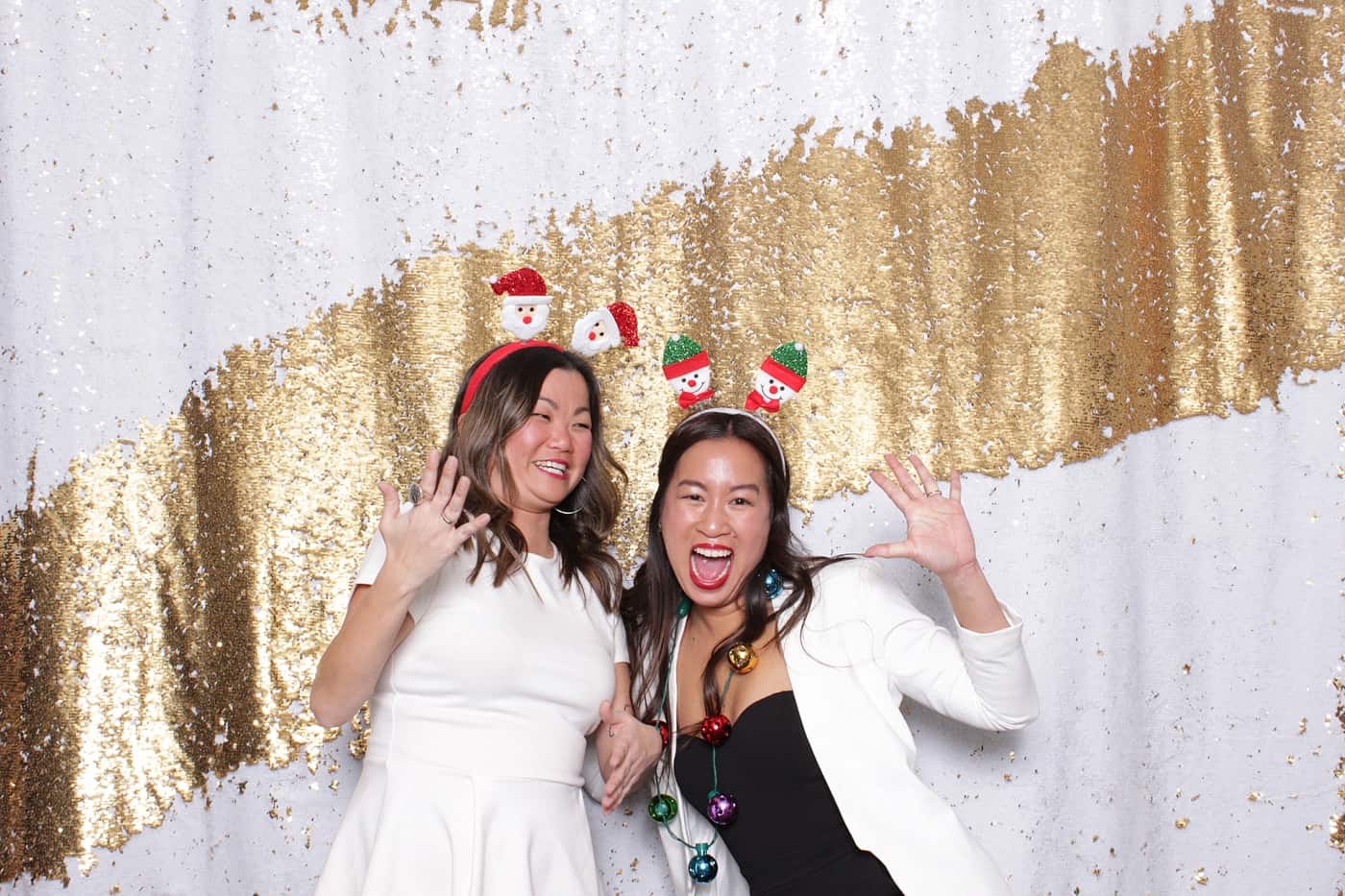 company christmas party photo booth photo taken against a white and gold sequin backdrop with christmas props